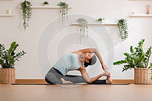 Calm of Asian woman in sportwear stretching muslce to warm up breathing and meditation with yoga at home.Healthy female doing yoga