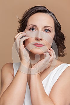 Calm attractive beautiful middle aged woman with wavy hair and makeup, looking at camera.