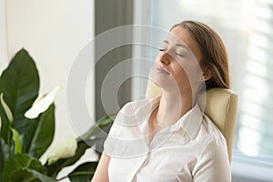 Calm attractive woman feeling relaxed leaning back on office cha