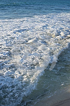 Calm beach waves with sea foam on the coast
