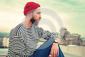 Calm bearded man sitting on the roof and looking into the distance