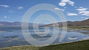 The calm and beautiful lake at the foot of the mountain reflects the blue sky, white clouds and mountains