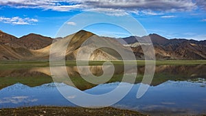 The calm and beautiful lake at the foot of the mountain reflects the blue sky, white clouds and mountains