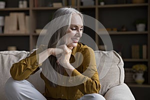 Calm beautiful middle-aged woman relaxing on cozy sofa