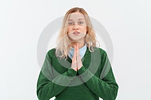 Calm beautiful young woman showing pray, namaste gesture, express gratitude, thank you sign, standing in green sweater over white