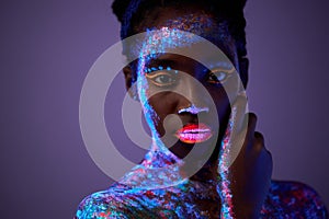calm black model woman in neon light. black model with fluorescent make-up