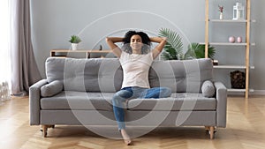 Calm black woman relaxing on comfortable sofa in living room