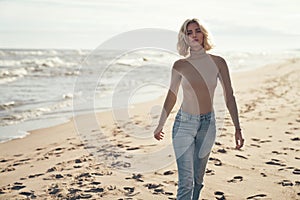 Calm, blond lady sauntering on a summer beach