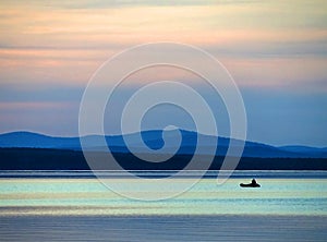 Calm blue sunset sky over the lake, silhouette of a lone boat with a fisherman, calm surface of water, lake Uvildy photo