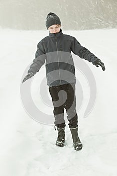 Calm boy walking in a path during snowstorm