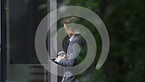 Calm business man going browsing digital tablet in urban office center outdoors.