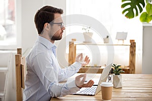 Calm businessman meditating at workplace practicing yoga focusing on concentration