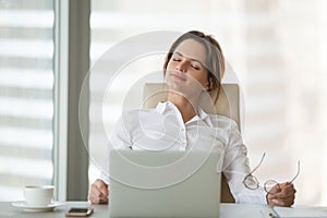 Calm businesswoman leaning in chair with eyes closed