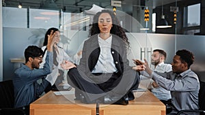 Calm businesswoman professional taking break meditating sitting at table in office meeting ignoring loud colleagues