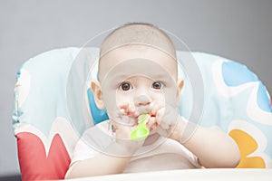 Calm caucasian infant in chair with small spoon