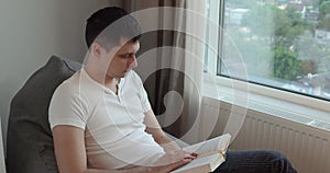 calm caucasian man reading book at home.