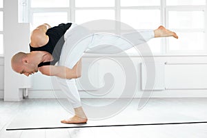 calm caucasian yogi male with bald head keep balance while performing posture on one leg