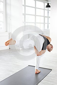 calm caucasian yogi male with bald head keep balance while performing posture on one leg