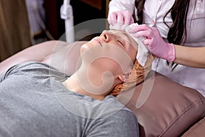 calm client man getting facial massage therapy in aesthetic medicine office