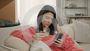 Calm concentrated lady with credit card using smartphone to pay online buy goods