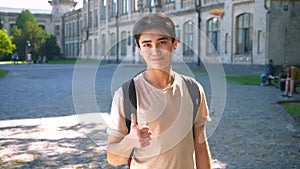Calm and confident asian man is showing like sign while standing on the street in sunlights with old building on