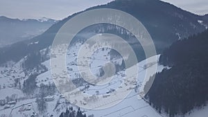 Calm and cosy fairy-tale village Kryvorivnia covered with snow in the Carpathians mountains, aerial view