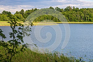 calm countryside lake river with cloud reflections in water and green shores