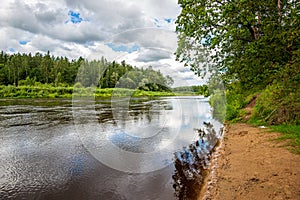 calm countryside lake river with cloud reflections in water and green shores