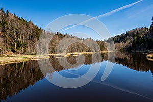 calm countryside lake river with cloud reflections in water and green shores