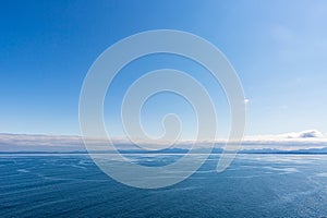 Calm dark blue sea with low clouds with land in the distance horizon