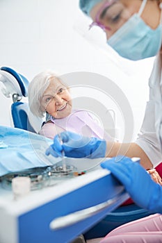 Calm dental doctor choosing bur while patient watching her