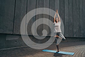 Calm elderly slim female practicing yoga outdoors