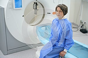 Calm elderly woman sits in CT room before diagnostic procedure