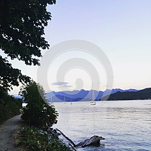 Calm evening in Howe Sound, outside of Gibsons, BC, Canada. A sailboat is sailing through the glassy ocean on the way to Gibsons.