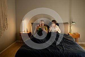 Calm family couple on retirement reading book together in bed