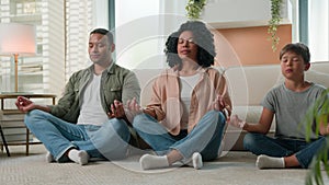 Calm family multiracial African American mother and father meditate with kid boy child yoga exercise in lotus pose on