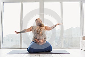 Calm fat man meditating near window