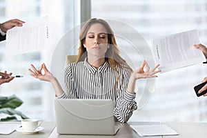 Calm female executive meditating taking break avoiding stressful job