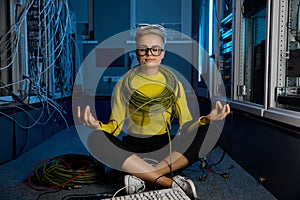Calm female IT technician meditating in server room
