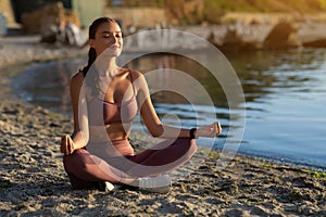 Calm female yogi sitting in lotus pose and meditating