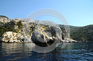 Calm and flat sea and a big rock in the middle of the sea.