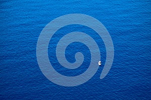 Calm flat surface of ocean and small fisher boat. Mediterranean Sea.