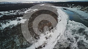 Calm, frozen river covered with ice on cold winter day. Peaceful river water and snowy coast on cold gray day in winter