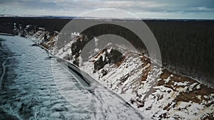 Calm, frozen river covered with ice on cold winter day. Peaceful river water and snowy coast on cold gray day in winter