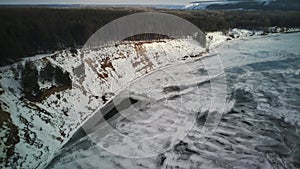 Calm, frozen river covered with ice on cold winter day. Peaceful river water and snowy coast on cold gray day in winter