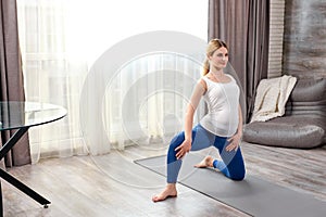 calm future mom-to-be, pregnant female in sportive clothes doing exercises on fitness mat