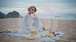 Calm girl enjoying coast picnic on cloudy weekend. Lonely lady resting beach