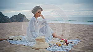 Calm girl enjoying coast picnic on cloudy weekend. Lonely lady resting beach