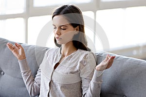 Calm woman meditate sitting on couch at home