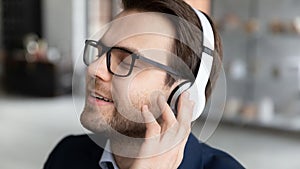 Calm happy businessman in headphones listen to music